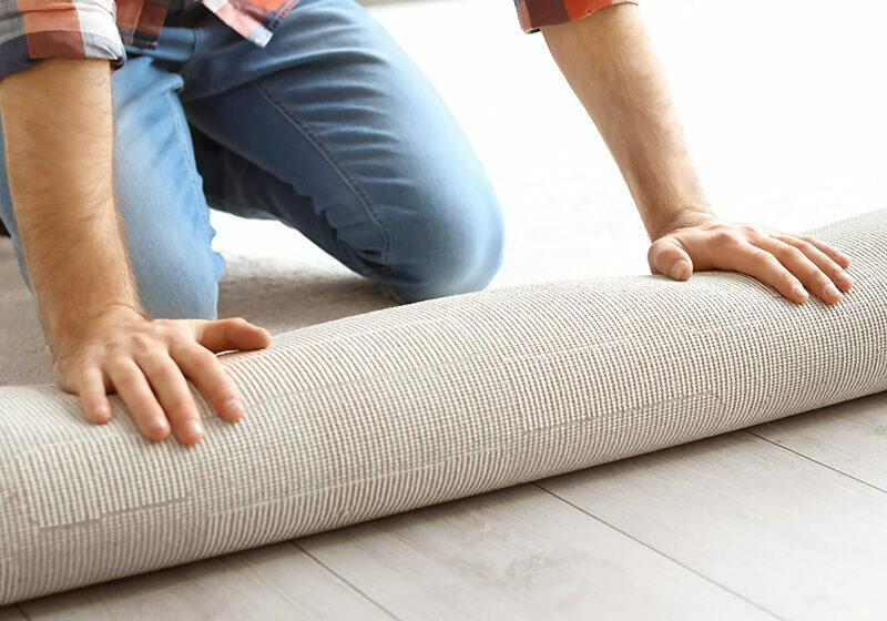 Man rolling out new carpet flooring in room | Jimmie Lyles Flooring Gallery
