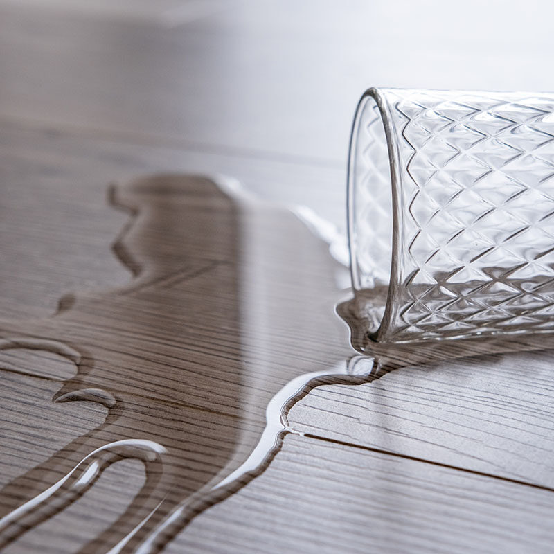 a glass of water spilled onto the floor. Waterproof laminate, concept.